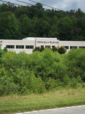 The Offices on Eleven building seen from route 11 behind green trees