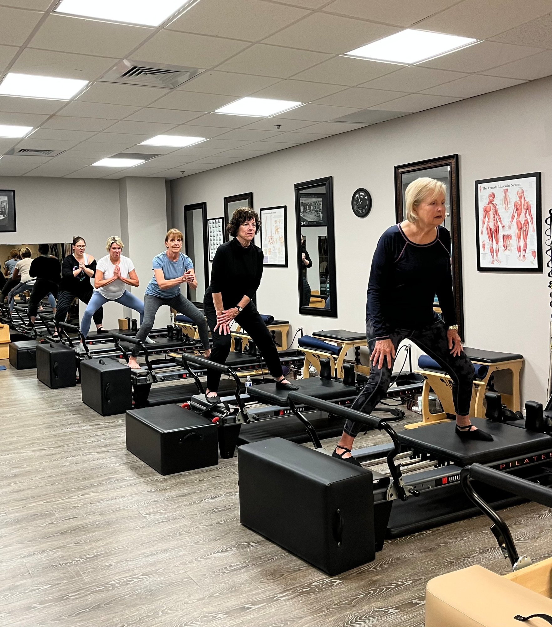 A small-group reformer class standing on the reformers in the studio