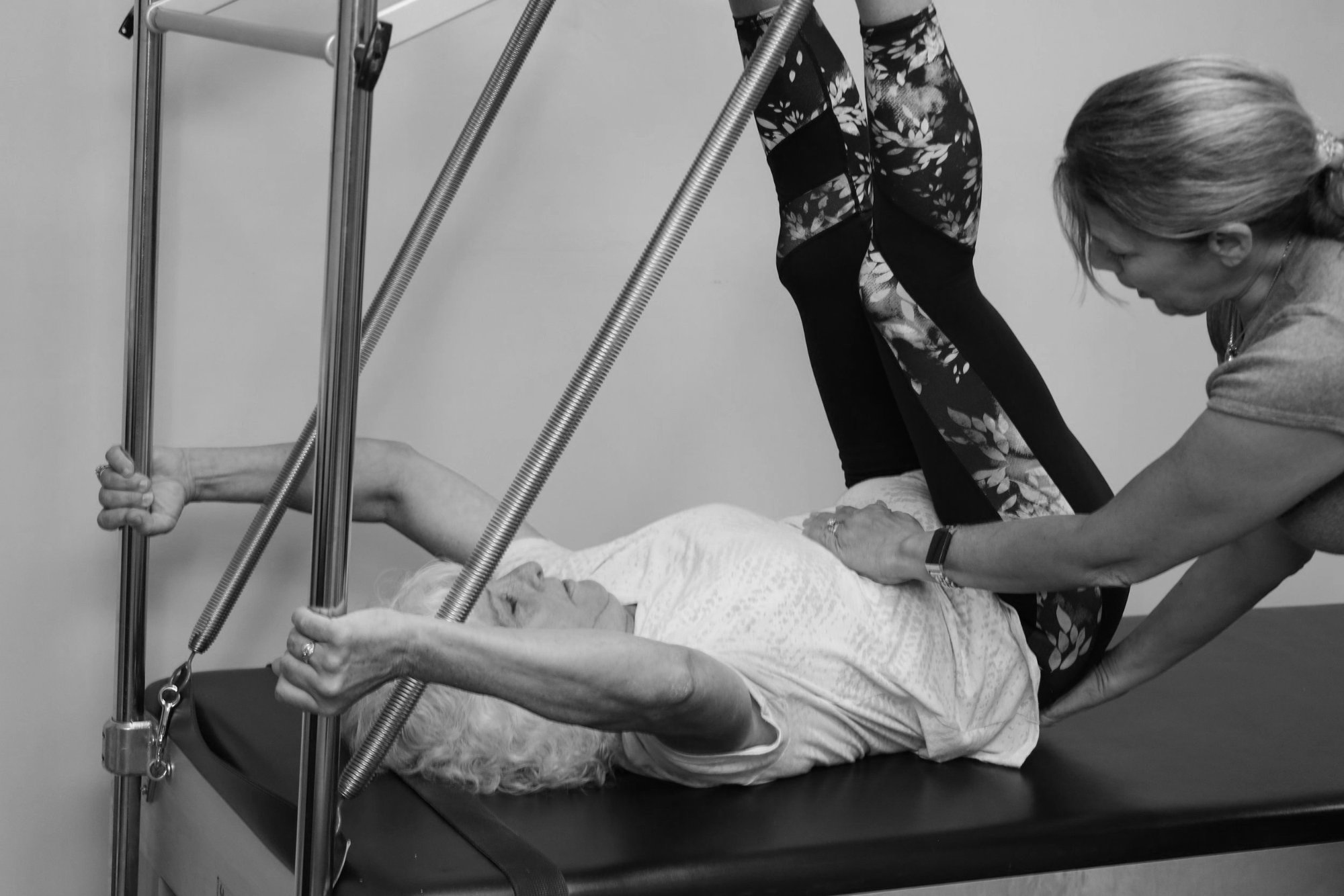 Black and white photo of a private session on the tower, with the instructor's hands guiding the client